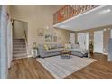 Bright living room featuring high ceilings, wood floors, a comfortable gray sofa, and a view of the upper level at 3067 Nuptial Ln, Lawrenceville, GA 30044
