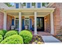 Inviting front porch with brick flooring, white columns, and rocking chairs, showcasing a welcoming entryway at 1830 Hadfield Blvd, Roswell, GA 30075