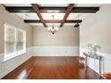 Elegant dining room with hardwood floors, decorative ceiling beams, and large window with modern chandelier at 245 Tapestry Dr, Mcdonough, GA 30252