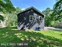 Back view of a dark gray house with a well-maintained lawn, trees, and a few items in the backyard at 4464 Cary Dr, Snellville, GA 30039