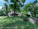 Two-story house surrounded by trees on a grassy hill, featuring a wooden deck and stairs at 4464 Cary Dr, Snellville, GA 30039