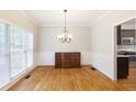 Formal dining room with hardwood floors, decorative chandelier, wainscoting, and a large window overlooking the yard at 5065 Hickory Hills Dr, Woodstock, GA 30188