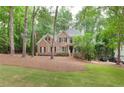 Traditional two-story brick home with manicured lawn, mature trees, and driveway at 5065 Hickory Hills Dr, Woodstock, GA 30188