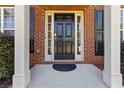 Close-up of a black front door framed by sidelights and white pillars in a brick facade at 310 Hammersmith Dr, Suwanee, GA 30024