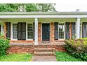 Close up of a brick front porch with black shutters, white columns and a black front door at 3916 Ridgewood Se Dr, Smyrna, GA 30080