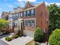 Angle view of a brick townhouse with a two-car garage and front porch, showcasing its architecture and landscaping at 1667 Wehunt Se Pl # 11, Smyrna, GA 30082