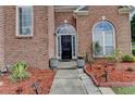 Close-up view of the home's entrance, featuring a black front door, arched windows, and colorful landscaping at 2678 Adair Trl, Dacula, GA 30019
