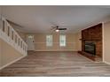 Open living room with a brick fireplace, ceiling fan, modern flooring, and lots of natural light at 535 Toonigh Rd, Woodstock, GA 30188