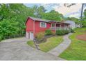 Side view of a red home with a driveway, two car garage and manicured landscaping at 2900 Country Nw Ct, Kennesaw, GA 30152