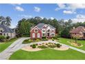 Charming two-story red brick home with beautiful landscaping, lush green lawn, and a curved driveway at 3364 Kylee Dawn Cir, Lawrenceville, GA 30045