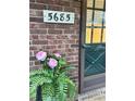 Close-up of house number and green door adorned with pink flowers in front of brick facade at 5685 Kingsport Dr, Sandy Springs, GA 30342