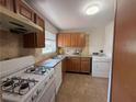 Functional kitchen with white appliances, wood cabinets, and tile flooring with laundry unit at 5685 Kingsport Dr, Sandy Springs, GA 30342