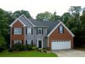 Charming two-story home featuring a brick and gray facade with a manicured lawn and lush landscaping at 5705 Cannonero Dr, Alpharetta, GA 30005