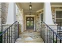 Inviting front porch with stone accents, iron railings, and a stylish double front door at 3298 Alcovy Club Ct, Dacula, GA 30019