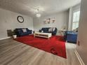 Bright living room featuring a red rug, comfortable blue sofas, and wood-look flooring at 5536 Strathmoor Manor Cir, Lithonia, GA 30058