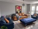 Bright living room featuring a leather sofa, a blue cushioned ottoman, and a modern chandelier at 5536 Strathmoor Manor Cir, Lithonia, GA 30058