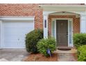 Welcoming brick townhome entryway featuring a covered porch and attached one-car garage at 7812 Kiverton Pl, Atlanta, GA 30350