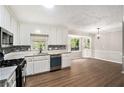Modern kitchen featuring white cabinets, mosaic backsplash, stainless steel appliances, and wood floors at 3333 Devaughn Ne Dr, Marietta, GA 30066
