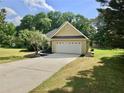 Side view of a home with an attached two-car garage, landscaped yard, and long driveway at 110 Orleans Blvd, Mcdonough, GA 30253