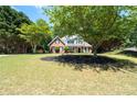 Charming two-story home with manicured lawn, brick facade, black shutters, and inviting front porch under tree at 2735 Princeton Trce, Cumming, GA 30041