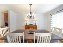 Elegant dining room with a modern chandelier, a wooden table, and views of the lush greenery outside at 503 Hearthstone Rdg, Woodstock, GA 30189