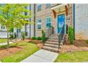Brick townhome entrance features a vibrant door, complemented by manicured landscaping, and charming details at 3313 Bartee Walk, Suwanee, GA 30024