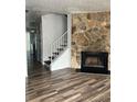 Bright living room featuring wood-look flooring, a stone fireplace, and a staircase with white railing at 458 Prince Of Wales, Stone Mountain, GA 30083