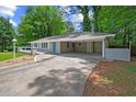 View of the home's facade with a carport and a paved driveway surrounded by lush landscaping at 1640 Fairburn Sw Rd, Atlanta, GA 30331