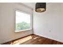 Bright room featuring hardwood floors, a modern light fixture, and a large window showcasing treetop views at 275 13Th Ne St # 605, Atlanta, GA 30309