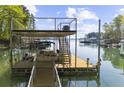 Multi-level boat dock on a tranquil lake with boat storage and a viewing platform under a partly cloudy sky at 3030 Heatherstone Dr, Cumming, GA 30041