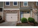 Close-up of a townhome facade showing a garage, front door, and stone detailing enhancing its curb appeal at 1296 Taylor Way, Stone Mountain, GA 30083