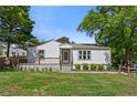 Charming home featuring a manicured front lawn, front porch, and beautiful trees on a sunny day at 313 Yancy Se Dr, Marietta, GA 30067