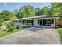 Ranch-style home featuring a vibrant blue front door, a cozy front porch, and a long driveway at 3627 Groovers Lake Rd, Lithia Springs, GA 30122