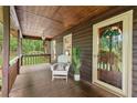 Inviting covered front porch with wood floors, a relaxing chair, and a view of the surrounding landscape at 4615 Gresham Rd, Douglasville, GA 30134