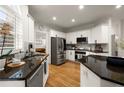 Modern kitchen with stainless steel appliances, granite countertops, white cabinets, and hardwood floors at 6790 Wolford Ct, Johns Creek, GA 30097