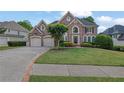 Charming two-story brick home with an attached two-car garage and a well-manicured lawn at 3143 Denton Ne Pl, Roswell, GA 30075