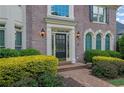 Elegant brick home entrance featuring a black door, manicured bushes, and a brick walkway at 3143 Denton Ne Pl, Roswell, GA 30075
