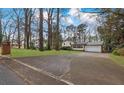 View of the home's front, circular driveway, lawn, and mature trees providing shade at 2325 Lago Dr, Jonesboro, GA 30236