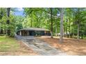 Full exterior view showing the home's architectural style, mature trees, driveway, and surrounding landscape at 715 Wood Valley Rd, Mableton, GA 30126