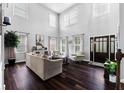 Bright living room with soaring ceilings, hardwood floors, and a cozy seating area, and dark-stained entryway door at 3016 Levinshire Way, Dacula, GA 30019