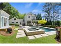 Backyard featuring a luxurious in-ground pool, spa, and lounge area surrounded by lush greenery at 4495 Westgate Dr, Cumming, GA 30040