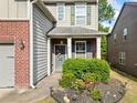 Inviting front entrance featuring a gray door, brick accents, and lush, manicured landscaping at 121 Camdyn Cir, Woodstock, GA 30188