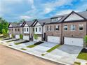 Row of townhomes featuring brick and siding exteriors, two-car garages, and neatly landscaped front yards under a blue sky at 5706 Urban Village Way # 4, Tucker, GA 30084