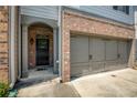 Close-up of the townhome's brick and gray-toned entryway, black front door and attached garage at 2249 Knoxhill Se Vw, Smyrna, GA 30082