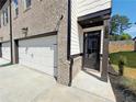 Close-up of the townhome front entry featuring a brick facade, white garage door, and black door at 5710 Urban Village Way # 6, Tucker, GA 30084