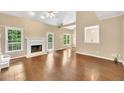 Open-concept living room with fireplace, hardwood floors, and natural light from large windows at 214 Kingsley Way, Woodstock, GA 30188