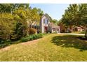 Well-manicured lawn and landscaping surround this two-story home with an attached two-car garage and mature trees at 515 Rosedown Way, Lawrenceville, GA 30043