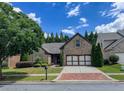 Desirable brick home featuring a driveway with brick trim, a two-car garage, and mature landscaping at 2826 Staunton Dr, Duluth, GA 30097