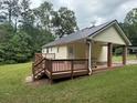 Home's backyard with a covered patio, steps leading to grass, and green trees in background at 42 Grant Nw Dr, Cartersville, GA 30121