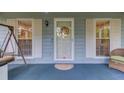 Close-up of the front door, featuring decorative wreath, sidelight windows with shutters, and covered porch at 1588 Peachtree Cir, Lawrenceville, GA 30043